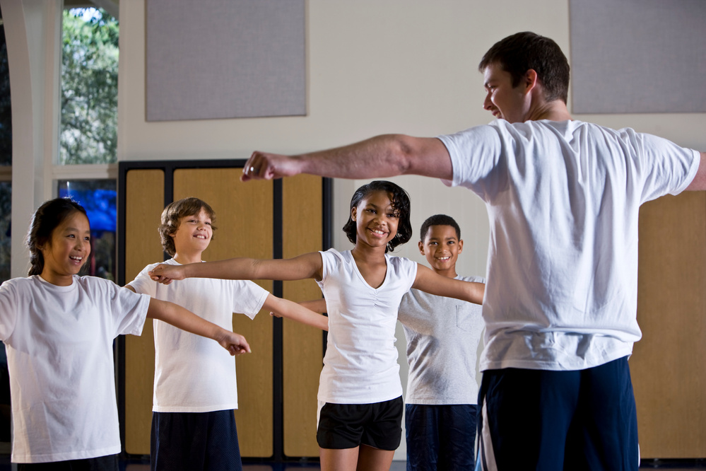 Diverse group of children in gym with physical education teacher